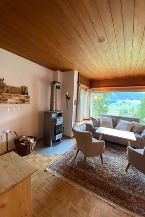 A cozy living room with a sofa, chairs, a fireplace, and a view of the outdoors. - Tga Muntanela Appartement/Fewo, Dusche und Bad, WC, 2 Schlafräume by Interhome (Savognin)