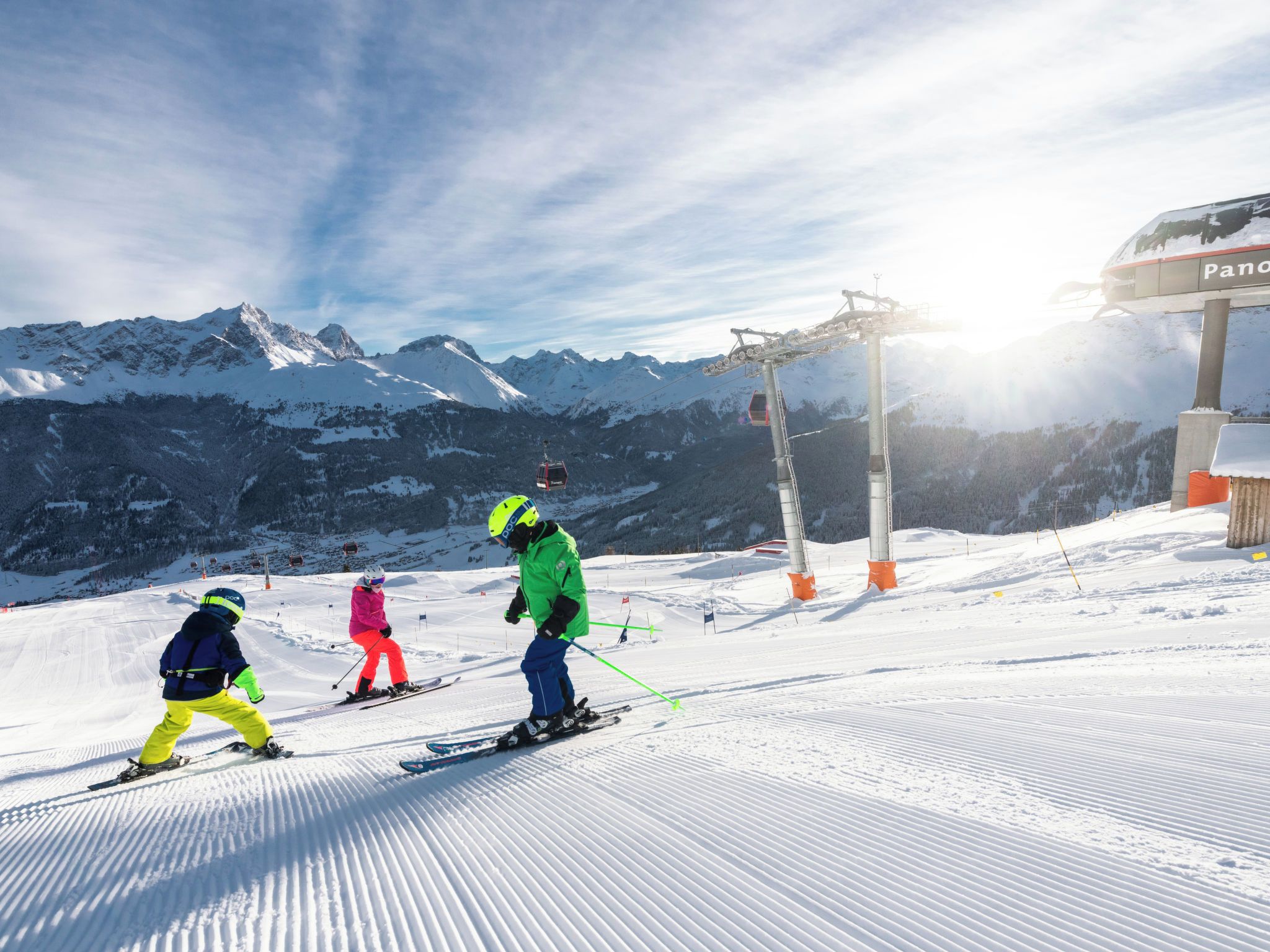 Skiers on a snowy slope with a mountain backdrop and a ski lift in the distance.