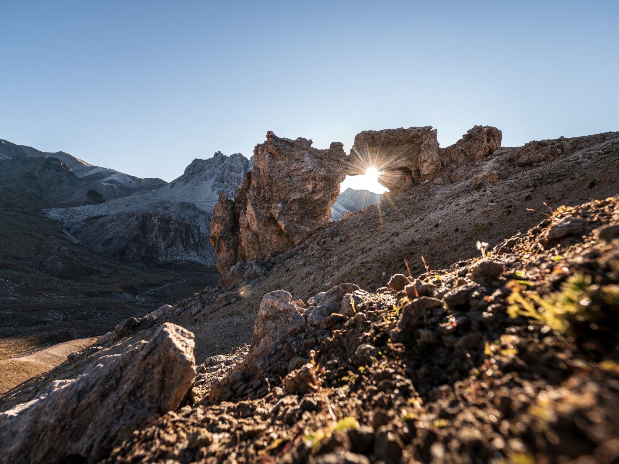 Un paisaje montañoso y agreste con una formación rocosa destacada y un cielo despejado.