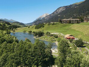 A lakeside resort with a view of mountains, a swimming area, and a building with multiple floors. - Bavegna Appartement/Fewo, Dusche und Bad, WC, 3 Schlafräume by Interhome (Savognin)