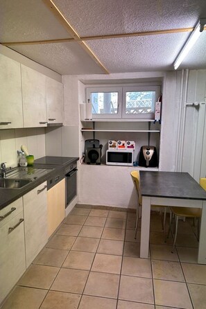 A compact kitchen with a built-in dishwasher, a microwave, and a small window. - Bavegna Appartement/Fewo, Dusche und Bad, WC, 3 Schlafräume by Interhome (Savognin)