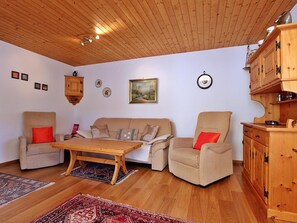 Ein gemütliches Wohnzimmer mit Holzboden, einer Sofagarnitur, einem Couchtisch und einem Schrank.