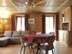 A cozy room with a wooden ceiling, a dining table with chairs, a sofa, and a cabinet with a painting. - Ferienwohnung Hof Collet Appartement/Fewo, Dusche oder Bad, WC, 1 Schlafraum by Interhome (Cunter)