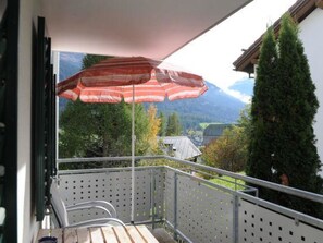 A balcony with a metal railing, a wooden bench, and a red umbrella. - Ferienwohnung Hof Collet Appartement/Fewo, Dusche oder Bad, WC, 1 Schlafraum by Interhome (Cunter)