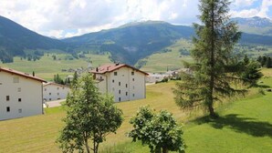 A residential area with multiple buildings, a grassy field, and mountains in the background. - Soras Zerbe/Hirth Appartement/Fewo, Bad, WC, 1 Schlafraum by Interhome (Savognin)