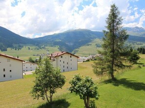 Ein Wohngebiet mit mehreren Gebäuden, einer grünen Wiese und Bergen im Hintergrund.