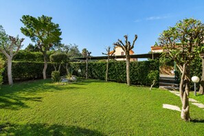 Ein gepflegter Garten mit Rasen, Bäumen und einem Gebäude mit rotem Dach.