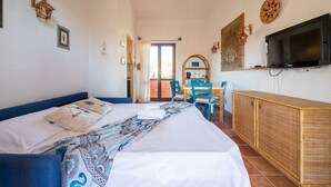 Una camera d'albergo con un letto, una televisione, una scrivania con una sedia e un armadio.