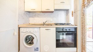 Una cucina compatta con lavatrice, forno e piano cottura a gas.