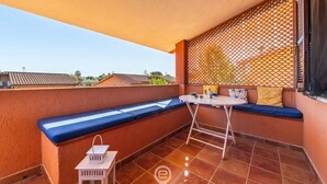 Un balcone con una panca imbottita blu, un tavolino e un lanterne bianco.