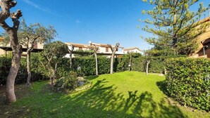 Un giardino curato con prato, alberi e un edificio con tetto in tegole.