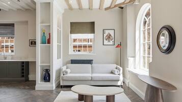 A living room with a sofa, a coffee table, and a view of a brick building through a window.