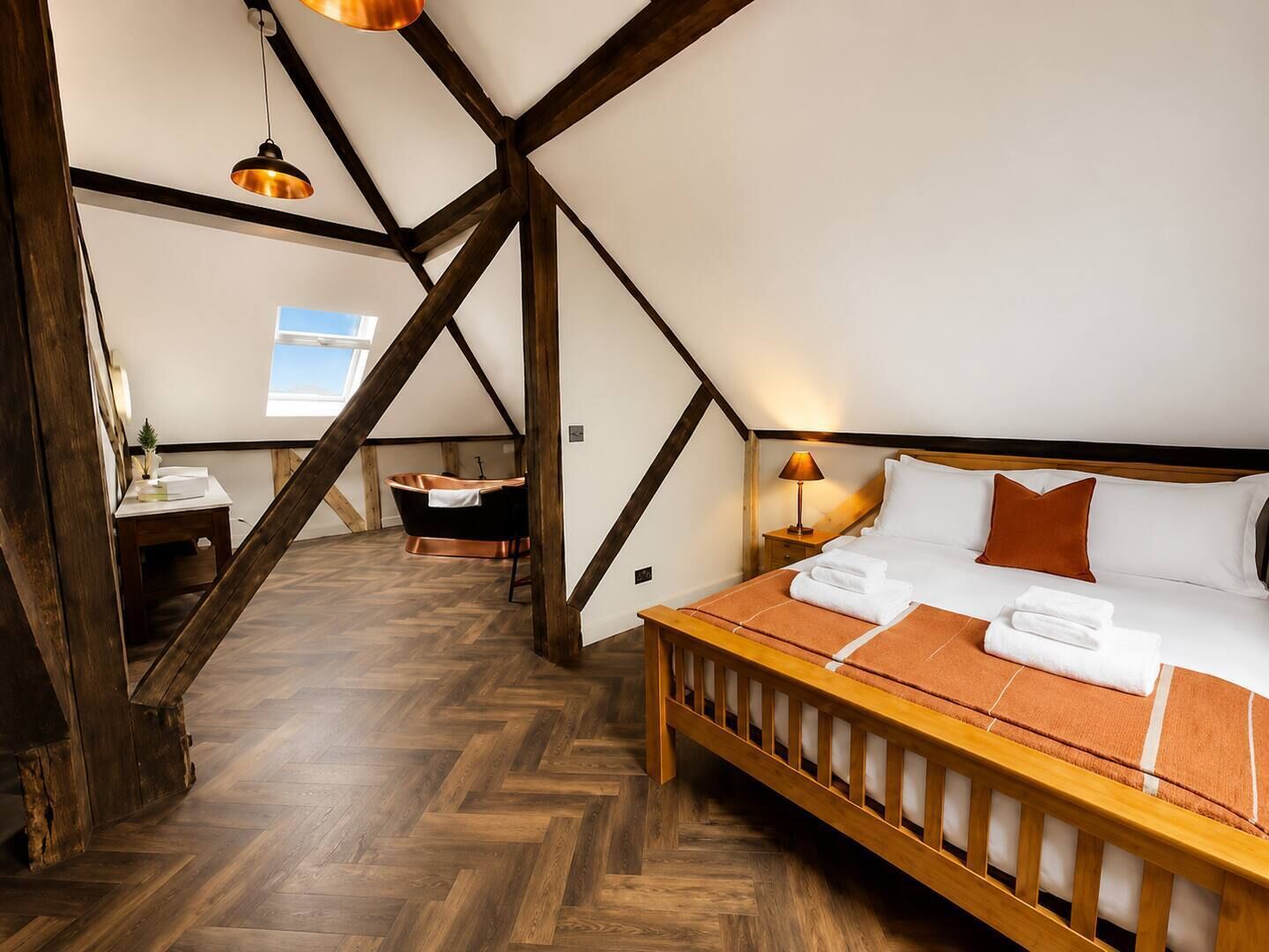 Ein Schlafzimmer mit einem hölzernen Bett, einem Nachttisch, einer Lampe, einem Fenster und einer Badewanne.