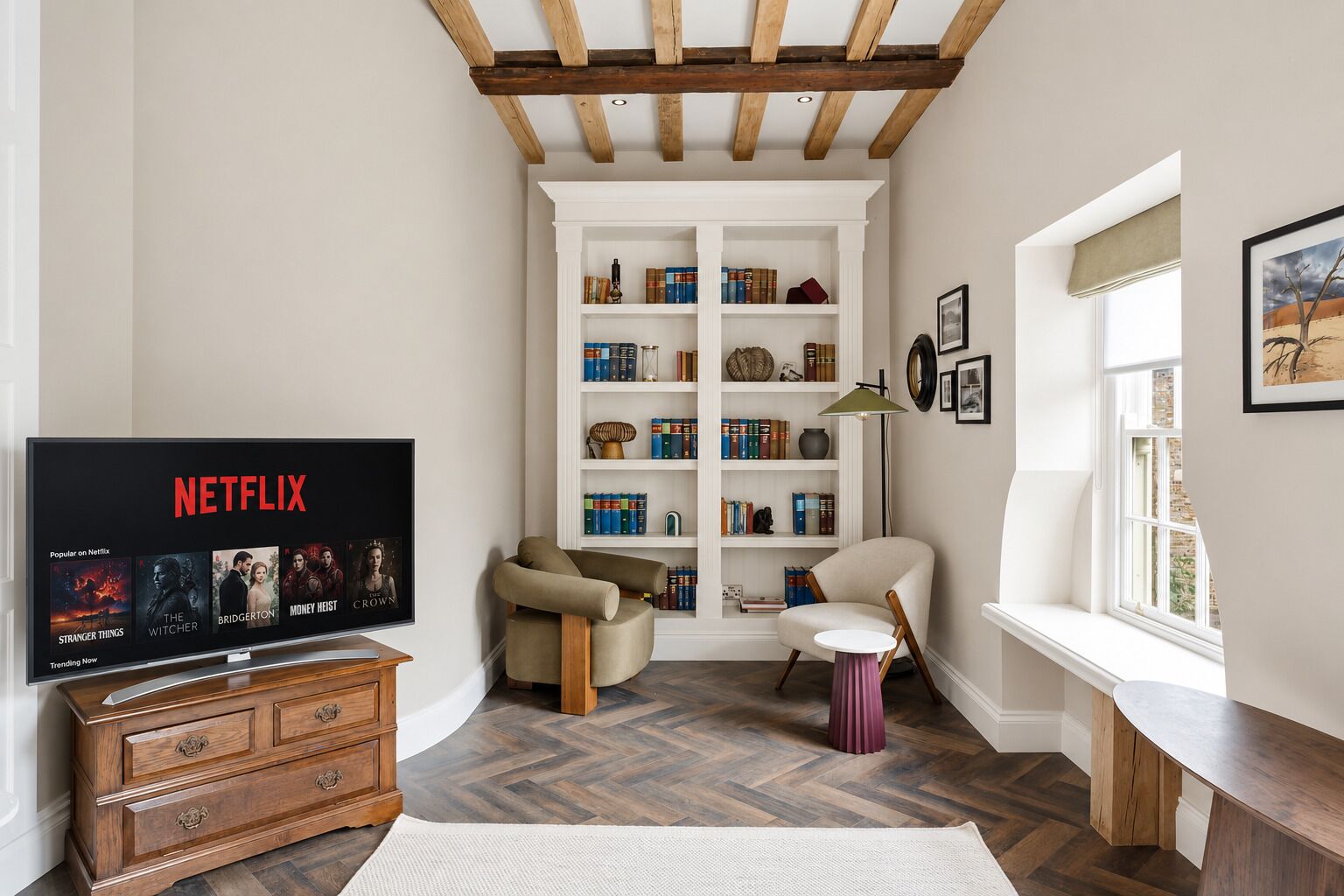 A cozy living room with a wooden TV stand, a bookshelf, and a window with a view.