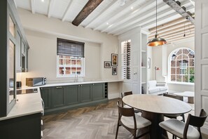 Een moderne keuken met donkere kastjes, een visgraatvloer en een eethoek met een ronde tafel en stoelen.