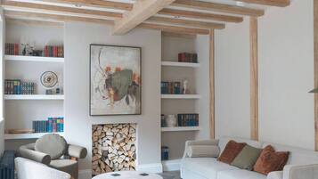 A living room with a white sofa, a round coffee table, and bookshelves filled with books and decorative items.