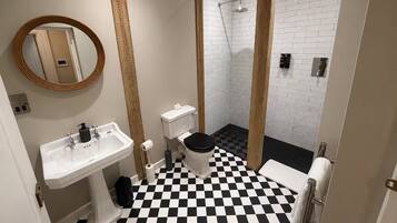 Un baño con piso a cuadros, un lavamanos, un inodoro y una zona de ducha.