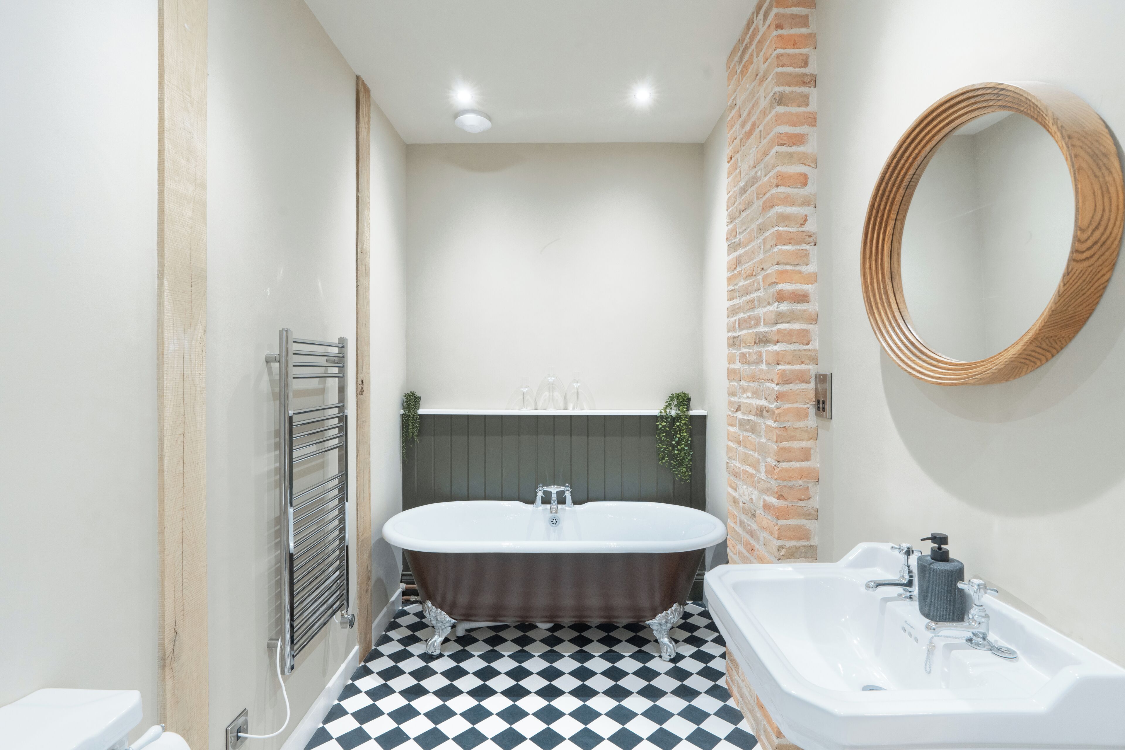 A bathroom with a freestanding bathtub, a sink with a mirror, and a tiled floor.