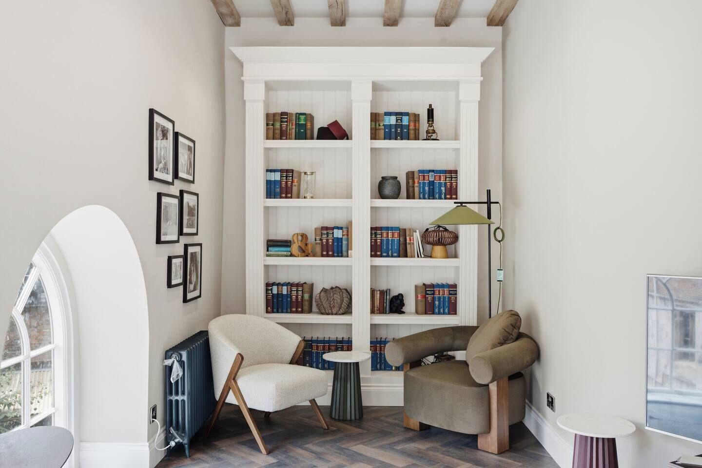A cozy reading nook with a bookshelf, a chair, a small table, and a lamp.