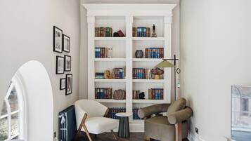 A cozy reading nook with a bookshelf, a chair, a small table, and a lamp.