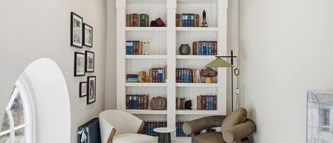 A cozy reading nook with a bookshelf, a chair, a small table, and a lamp.