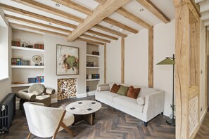 A living room with a white sofa, a round coffee table, and a bookshelf filled with books.