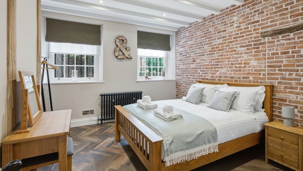 Ein Schlafzimmer mit einem hölzernen Bett, einem Schreibtisch und einer Ziegelwand.