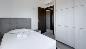 Ein modernes Hotelzimmer mit einem großen Bett, einem Kleiderschrank und einer Klimaanlage.