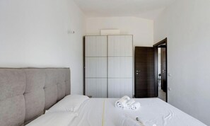 Una camera d'albergo con un letto, una testiera, un armadio e una porta.