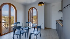 Ein Essbereich mit Glastisch und Stühlen, großen Bogenfenstern und Blick ins Freie.