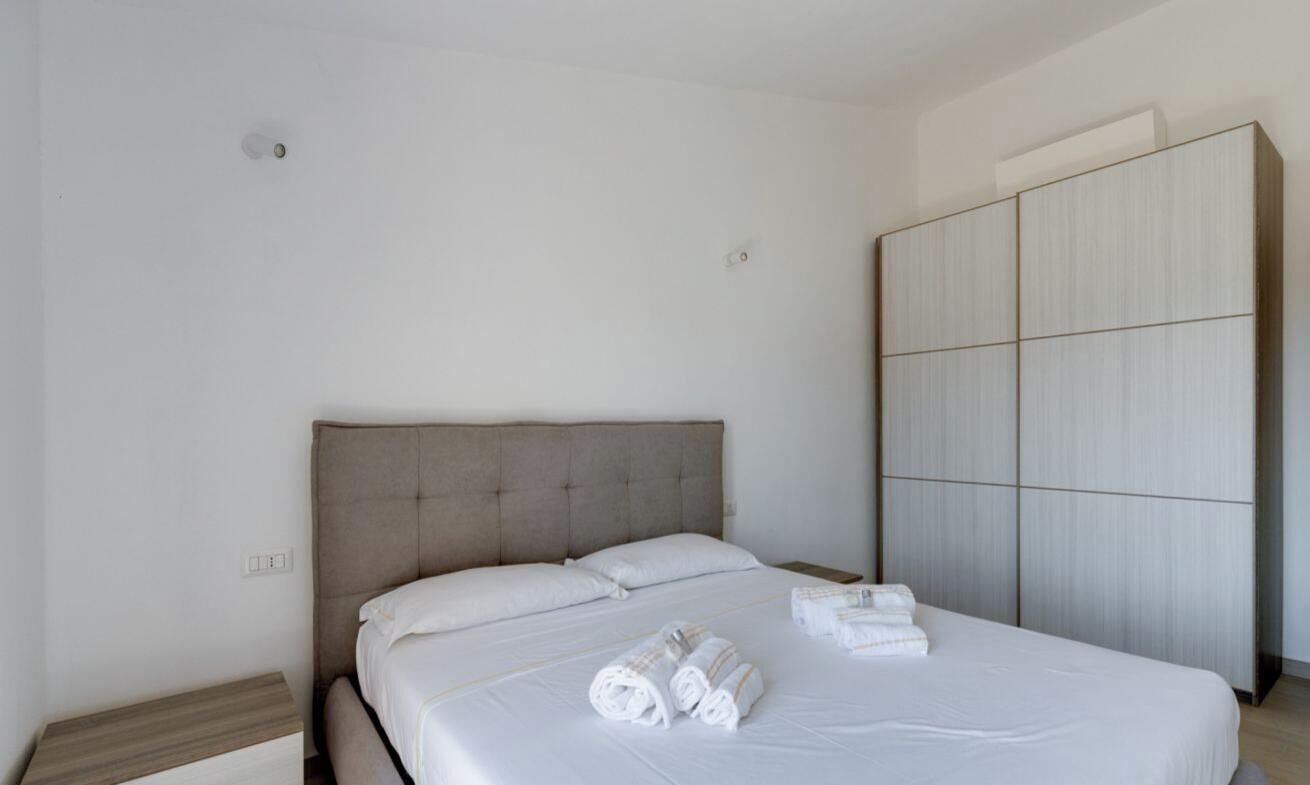 Habitación de hotel con una cama grande, un armario y toallas dobladas con cuidado sobre la cama.