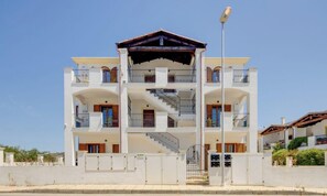 A multi-story building with balconies, a central staircase, and a covered entrance. - Mandarin Apartment 5 (Tortolì)