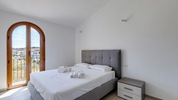 Ein Schlafzimmer mit einem Bett, einem Nachttisch, einem Fenster mit Aussicht und einer Tür.