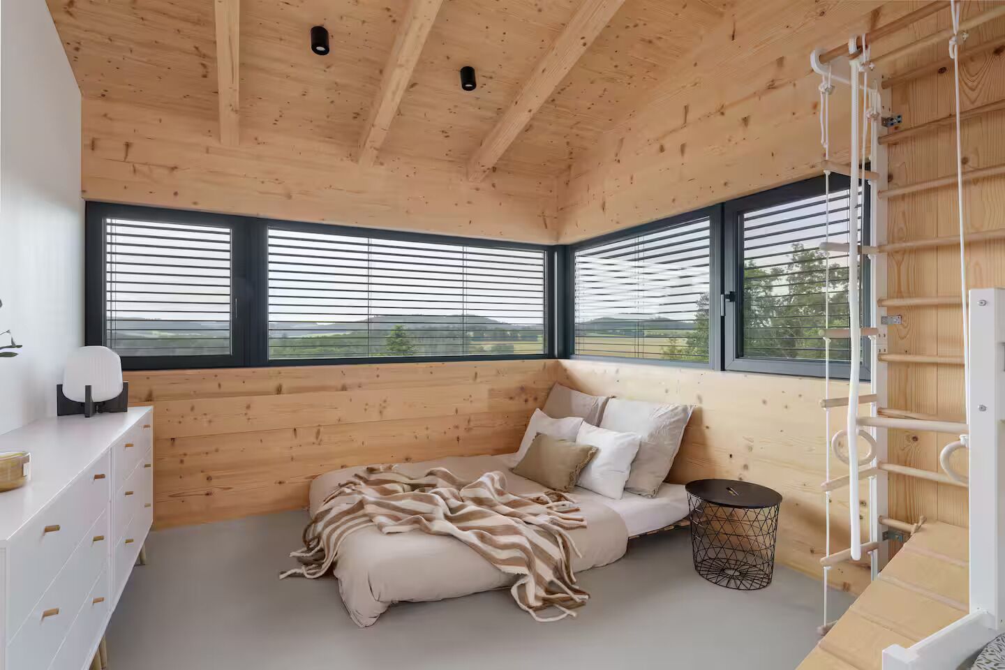Une chambre à coucher avec un lit, une table de chevet, une lampe et une fenêtre avec des stores.
