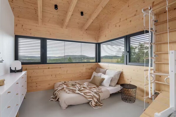 A bedroom with a bed, a bedside table, a lamp, and a window with blinds.
