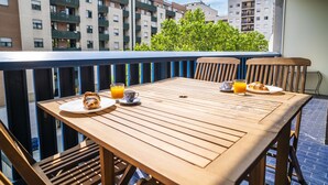 Un tavolo di legno con cibi per la colazione su un balcone affacciato su una zona residenziale.