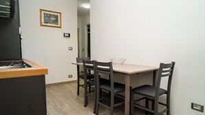 Una cucina compatta con un piano di lavoro in legno, un piano cottura integrato e un tavolo da pranzo con quattro sedie.
