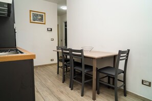 A compact kitchen with a wooden countertop, a built-in stove, and a dining table with four chairs. - Il Bacio - Guest House (Perugia)