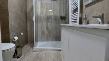 Ein modernes Badezimmer mit Duschkabine aus Glas, Toilette und Waschtisch mit Spiegel.