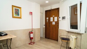 Un corridoio con un estintore, un telefono, una porta con istruzioni di emergenza e una finestra.