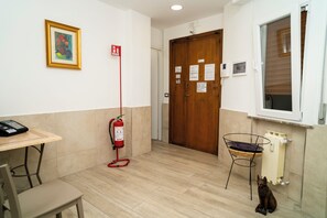 A hallway with a fire extinguisher, a telephone, a door with emergency instructions, and a window. - Il Bacio - Guest House (Perugia)
