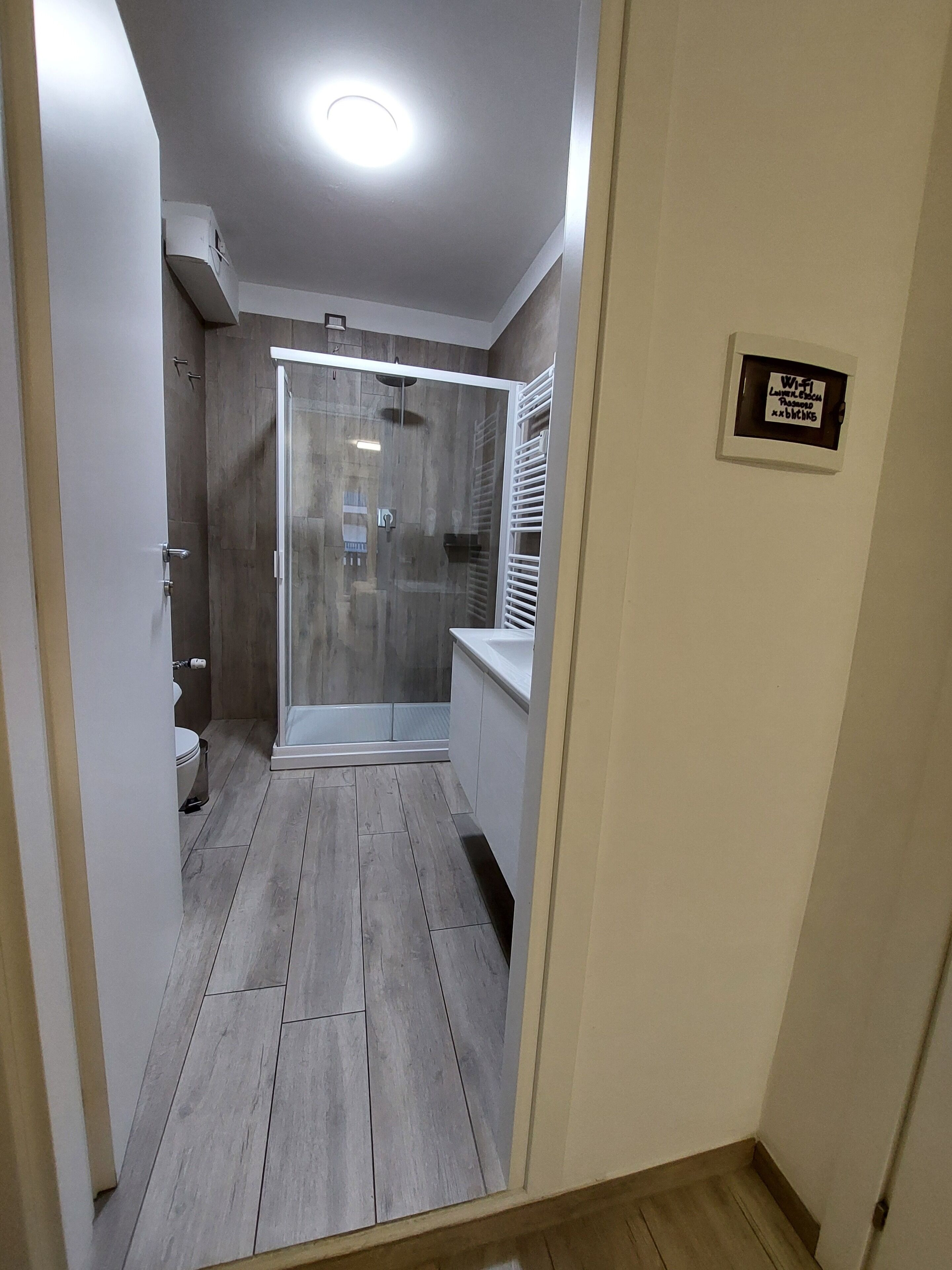 A modern bathroom with a glass shower enclosure, a toilet, and a sink.