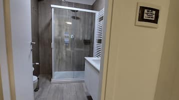 Un baño moderno con cabina de ducha de vidrio, inodoro y lavamanos.