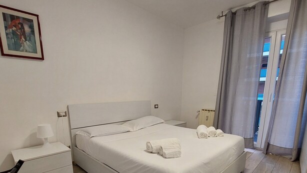 Una camera da letto con un letto, un comodino, una sedia e una finestra con tende.
