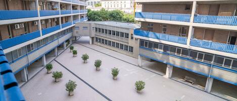 A multi-story building with balconies, a central courtyard with potted plants, and a building with a modern design.