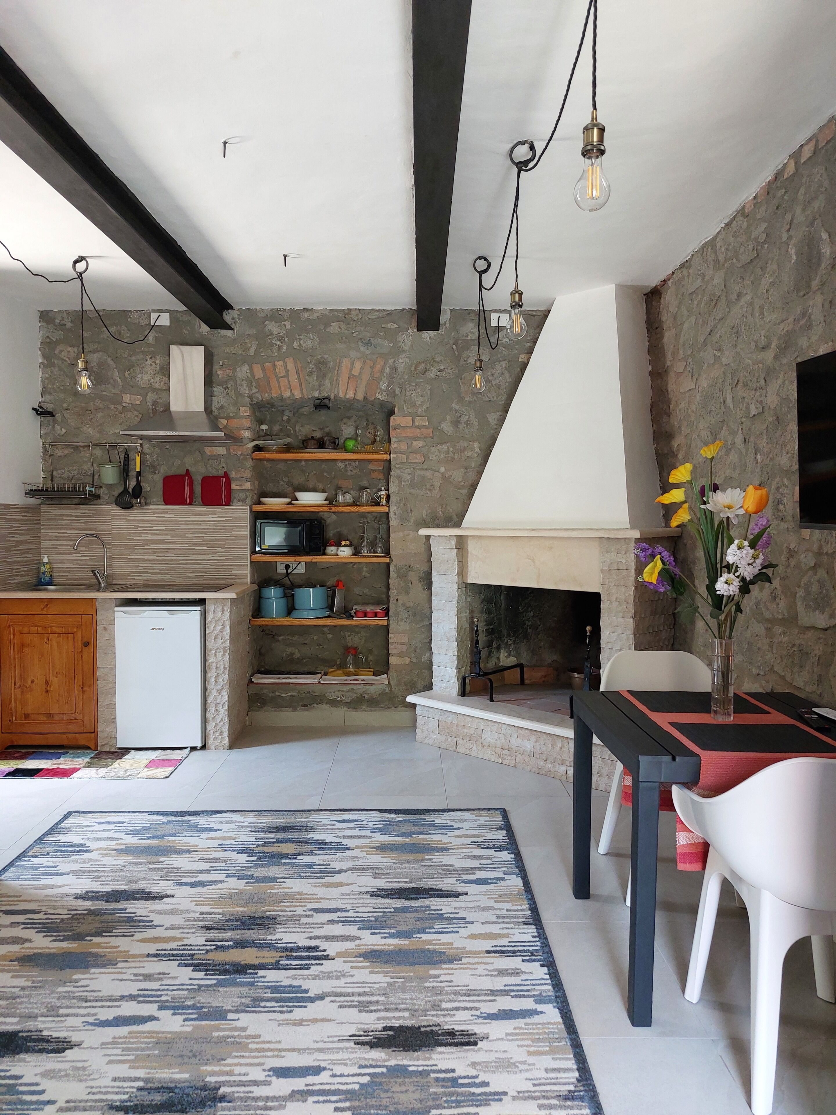 Una cocina moderna con pared de piedra, repisas de madera y horno empotrado.