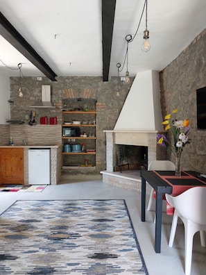 Una cocina moderna con pared de piedra, repisas de madera y horno empotrado.