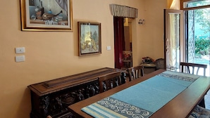 Un comedor con una larga mesa de madera, sillas y dos cuadros enmarcados en la pared.