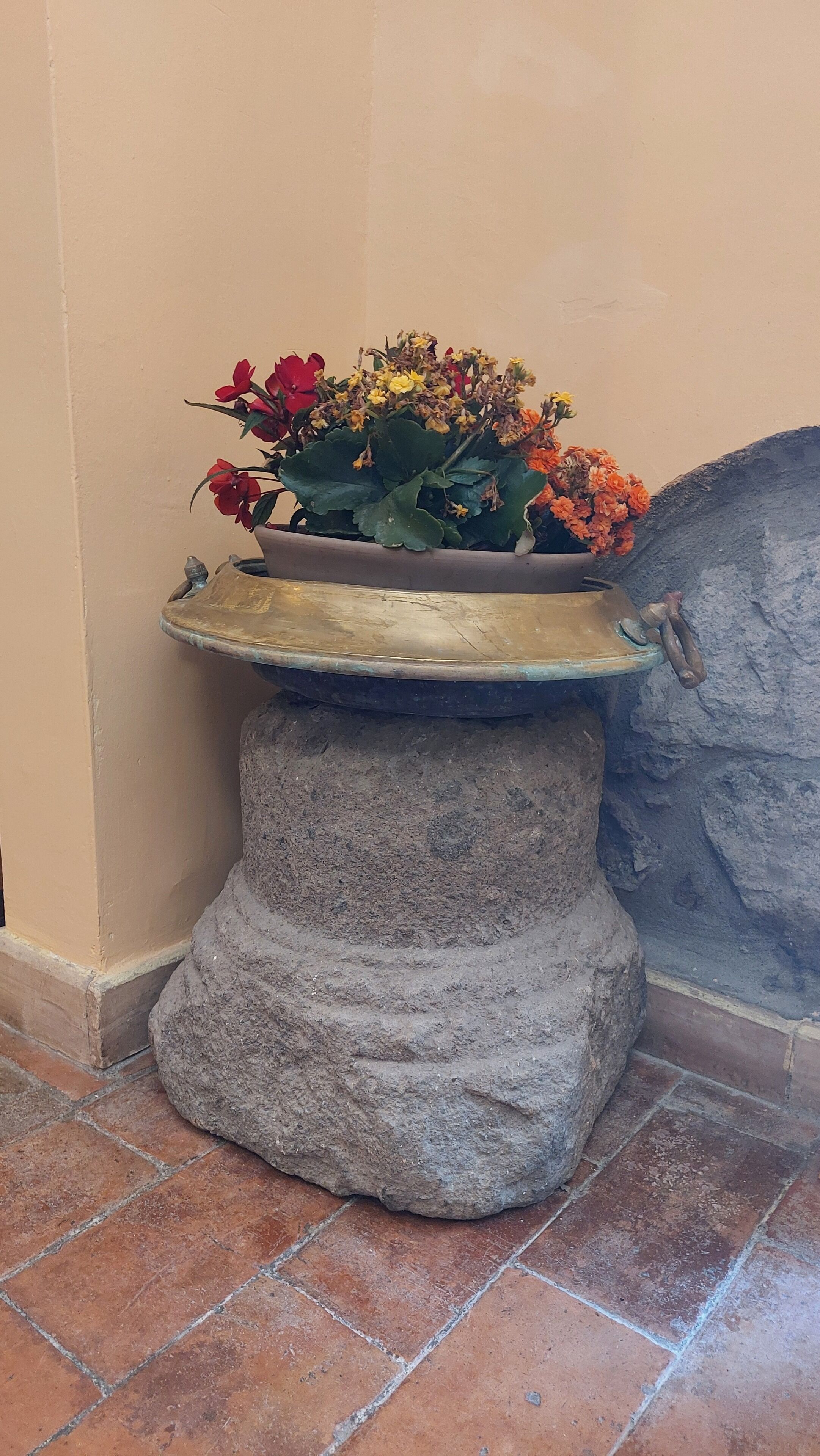 Un bac à fleurs en pierre agrémenté d’une composition florale.