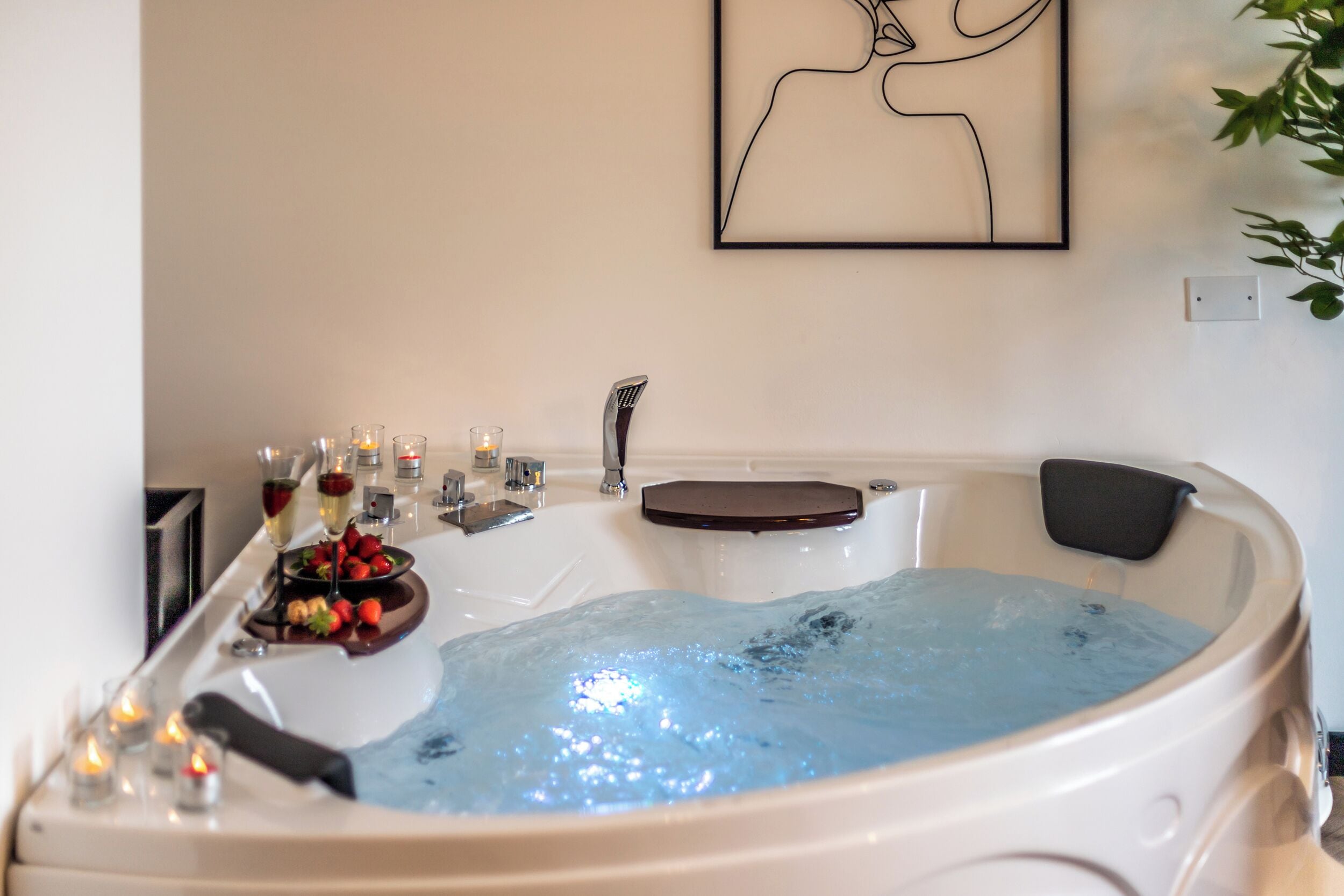 A hot tub with a wooden seat, surrounded by candles and fruit.